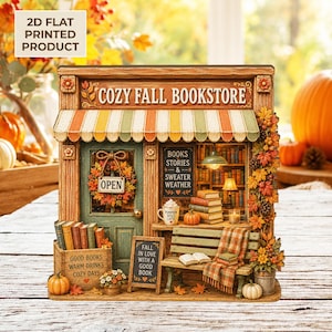 Peut inclure: Un produit imprimé plat 2D représentant la devanture d'une librairie avec le texte COZY FALL BOOKSTORE, un auvent rayé, une porte verte avec une couronne OPEN, un banc avec une couverture à carreaux, des livres, des citrouilles et du feuillage.