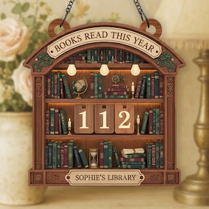 May include: Wooden bookshelf-shaped sign with the text "BOOKS READ THIS YEAR" and "SOPHIE'S LIBRARY". The sign has a shelf with miniature books, a globe, candles, and the number "112". It hangs from a chain.