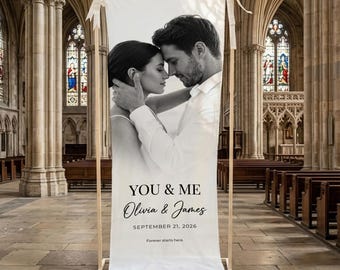 May include: A white banner with a black and white photo of a couple embracing. The banner reads "YOU & ME" with the names "Olivia & James" and the date "SEPTEMBER 21, 2026". The banner is displayed on a wooden frame.