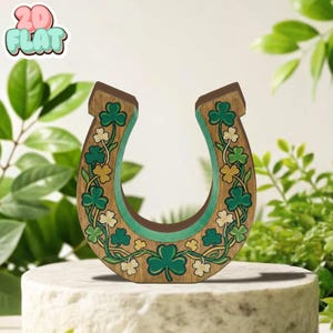 Op de afbeelding: Houten hoefijzerdecoratie met een klaverontwerp in groen en goud. Het hoefijzer is bruin met een groene binnenkant en versierd met klavers en bloemen. De tekst "2D FLAT" staat in de linkerbovenhoek.