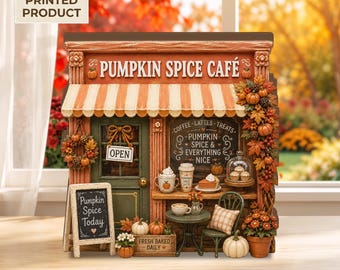 May include: A 2D flat printed decorative sign shaped like a Pumpkin Spice Café storefront. The design features a striped awning, a green door with an open sign, a chalkboard menu, a small table with chairs, and autumn-themed pumpkin decor.