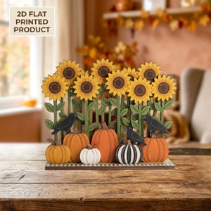 May include: A 2D flat printed decorative display featuring a row of yellow sunflowers on green stems, orange and white pumpkins, and black crows. The base is rectangular with a checkered pattern. Text on the image reads 2D FLAT PRINTED PRODUCT.