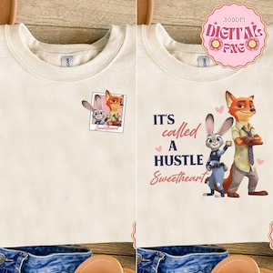 May include: Cream-colored sweatshirt featuring two designs. One shows Judy Hopps and Nick Wilde in a photo frame with "Sweetheart" text. The other design has the characters with the text "It's called a HUSTLE Sweetheart" and pink hearts.