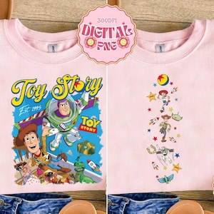 May include: Two light pink sweatshirts with Toy Story graphics. One features Buzz Lightyear and Woody with the text "Toy Story Est. 1995". The other has a vertical design of characters and rockets. Both have a crew neck.