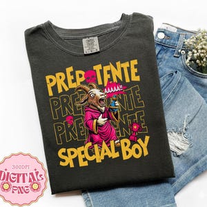 Könnte beinhalten: Ein anthrazitfarbenes T-Shirt mit einer Grafik einer Ziege in einem rosa Gewand, die eine blaue Zaubertrankflasche hält und neben einem Pokal steht. Der Text lautet PREPOTENTE und SPECIAL BOY in Gelb, mit einem rosa Totenkopf und AAAAA!!.