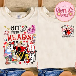May include: Cream-coloured t-shirt with a colourful graphic from Alice in Wonderland. The front design includes the text "Off With Their Heads!" and various characters. The back has a smaller design with the text "Queen of Hearts".