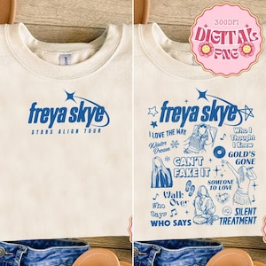 Peut inclure: Sweat-shirt crème avec l'inscription bleue "freya skye STARS ALIGN TOUR". Le motif comprend des titres de chansons et des graphiques bleus. Un graphique rose "DIGITALS PNG" est dans le coin supérieur droit.