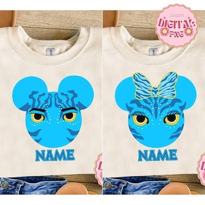 Könnte beinhalten: Zwei cremefarbene Sweatshirts mit blauen Avatar-Charakterdesigns. Eines zeigt einen männlichen Charakter mit ernstem Gesichtsausdruck, das andere einen weiblichen Charakter mit einer Schleife. Beide haben das Wort "NAME" darunter.