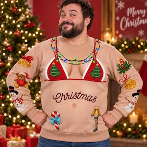 Puede incluir: Una sudadera beige de manga larga con un gráfico de un top de bikini rojo con árboles de Navidad verdes, una cadena de luces de colores y la palabra Christmas. Las mangas y la parte delantera muestran varios iconos navideños, incluyendo muñecos de nieve, un oso de peluche, un bastón de caramelo y una lámpara de pierna.