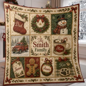 May include: A quilted throw blanket featuring a grid of Christmas illustrations including a stocking labeled Dad, a wreath, a snowman, a red truck, a mug labeled Mom, a tag labeled James, a gingerbread man, an ornament labeled Annie, and a bone labeled Kio.