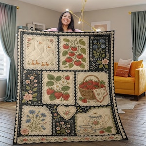 May include: A quilted blanket featuring a patchwork design with various embroidered images. The images include geese, tomatoes, strawberries, flowers, and a teapot. The blanket has a black background with white lace trim.