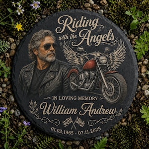 May include: A round black slate memorial plaque featuring an illustration of a bearded person in a leather jacket and sunglasses next to a motorcycle with wings. Text reads Riding with the Angels, In Loving Memory, William Andrew, 01.02.1965 - 07.11.2025.