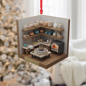 May include: A wooden Christmas ornament shaped like a pottery studio. The ornament features miniature shelves with pottery, a kiln, and a pottery wheel. The text "David Pottery Studio - 2025" is visible on the front. A red ribbon is attached for hanging.