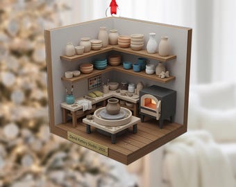 Può includere: Un ornamento natalizio in legno a forma di studio di ceramica. L'ornamento presenta scaffali in miniatura con ceramiche, un forno e un tornio. Il testo "David Pottery Studio - 2025" è visibile. Un nastro rosso è attaccato per appenderlo.