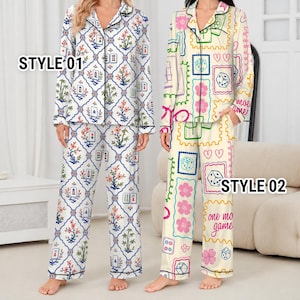 May include: Two sets of long-sleeved button-down pajamas. Style 01 features a white background with a blue lattice pattern, floral motifs, and mahjong tiles. Style 02 has a cream background with colorful dice, hearts, flowers, and the text one more game.