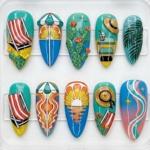 May include: A set of ten artificial nails with a summer beach theme. Each nail features a unique design, including beach chairs, umbrellas, cacti, and sunsets. The nails are painted in vibrant colors like turquoise, yellow, and orange, and are encased in a clear plastic container.