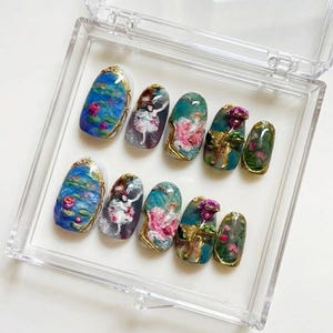 Puede incluir: Un juego de diez u&ntilde;as artificiales en una caja de pl&aacute;stico transparente. Cada u&ntilde;a presenta un dise&ntilde;o &uacute;nico, que incluye nen&uacute;fares, bailarinas y detalles florales, con ribetes dorados. Las u&ntilde;as son de forma ovalada y tienen un acabado brillante.