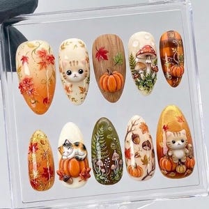 May include: A set of ten almond-shaped press-on nails featuring autumn-themed designs including 3D cats, orange pumpkins, red and yellow maple leaves, mushrooms, acorns, and forest foliage patterns, all displayed within a clear plastic storage case.