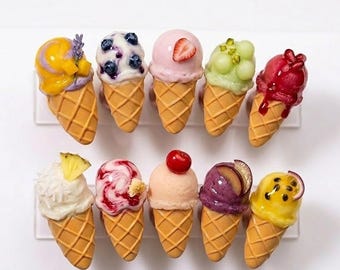May include: Ten miniature ice cream cones arranged in two rows. Each cone features a different flavor with toppings including blueberries, strawberry slices, pineapple wedges, cherries, passion fruit, and lavender sprigs on textured waffle cones.
