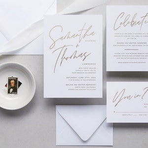 May include: Gold foil wedding invitation suite with a white background. The main invitation features the couple's names, "Samantha + Thomas", in a modern calligraphy font. The RSVP card features the text "You in?" in the same font.