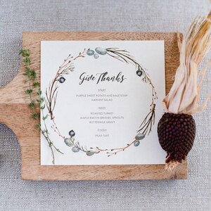 K&ouml;nnte beinhalten: Eine Thanksgiving-Men&uuml;karte mit einem Aquarell-Kranz-Design. Das Men&uuml; beinhaltet: Lila S&uuml;&szlig;kartoffel- und Gr&uuml;nkohlsuppe, Erntessalat, gebratenen Truthahn, Ahorn-Speck-Rosenkohl, Buttermilchso&szlig;e und Birnenkuchen.