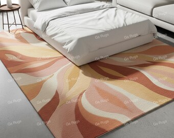 May include: A rectangular area rug with a swirling, abstract design in shades of peach, orange, and cream. The rug is placed on a concrete floor beneath a white bed. The rug's pattern resembles stylized flower petals.