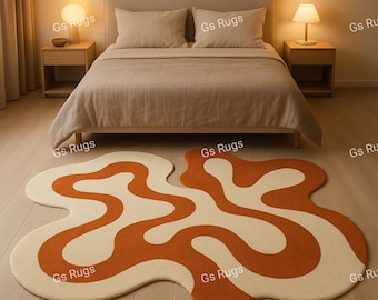 May include: A bedroom scene featuring a bed with beige bedding and two matching nightstands with lamps. Two abstract rugs with an orange and cream wavy design are on the wooden floor. The rugs are labeled "Gs Rugs".