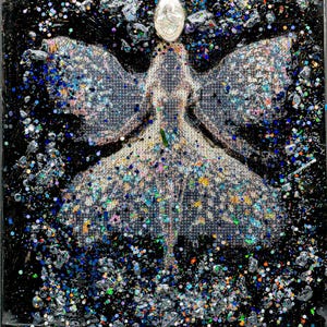 May include: Abstract artwork featuring a central figure with outstretched wings, adorned with glitter and iridescent accents. The background is black, with scattered glitter and a decorative oval at the top. The artwork is a mixed media piece.