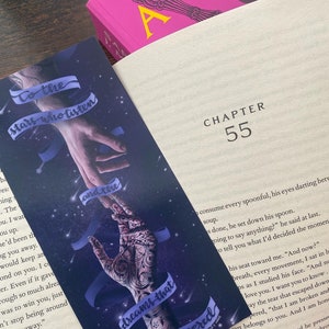 May include: A bookmark with a dark blue background and a starry sky. Two hands are reaching towards each other with the text "To the stars who listen" and "dreams that are answered" on the bookmark.