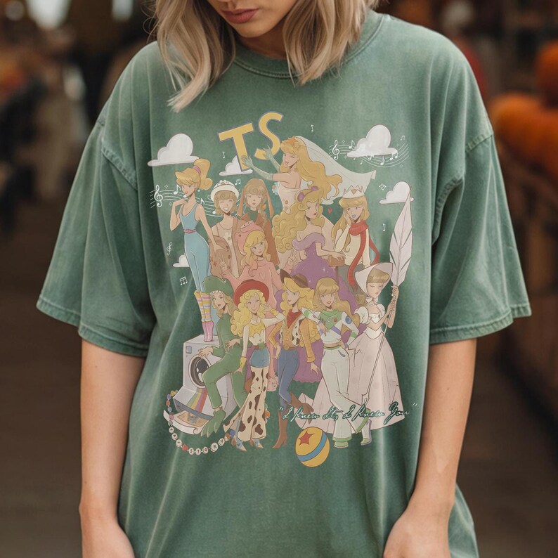 Puede incluir: Una camiseta de manga corta color verde salvia con un estampado gr&aacute;fico de varios personajes animados, las letras TS y el texto I Know It, I Know You. El dise&ntilde;o incluye notas musicales, nubes, una c&aacute;mara y una pelota con una estrella roja.