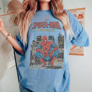 May include: A white ceramic mug with a black handle and the text "But First, Coffee" in a black, handwritten-style font. The mug is on a white surface.