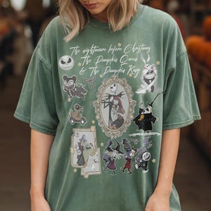 Pu&ograve; includere: T-shirt verde con personaggi e testo da "Nightmare Before Christmas". Il design include Jack Skellington, Sally e altri personaggi in stile vintage. Il testo recita "The Nightmare Before Christmas, The Pumpkin Queen & The Pumpkin King."