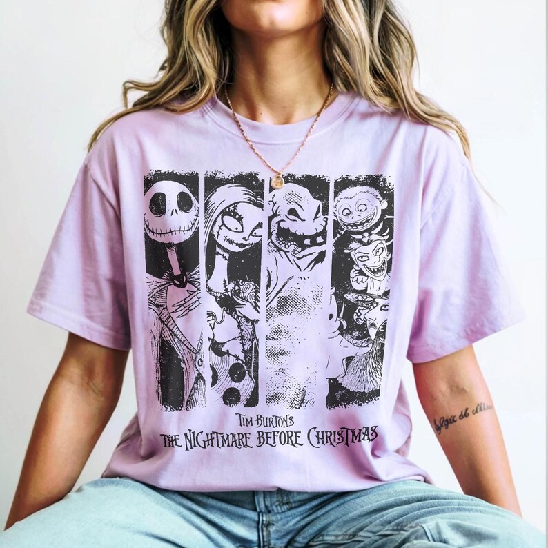May include: A light purple short-sleeve t-shirt featuring a black graphic print of characters from Tim Burton's The Nightmare Before Christmas. The design includes four vertical panels showing Jack Skellington, Sally, Oogie Boogie, and Lock, Shock, and Barrel.