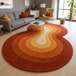 Könnte beinhalten: Ein runder Teppich im Retro-Design. Der Teppich hat konzentrische, wellenförmige Farbbänder, die von einem tiefen Rot-Orange am äußeren Rand zu einem hellen Gelb in der Mitte übergehen. Der Teppich besteht aus einem weichen Material.