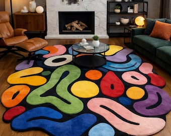 May include: A colorful, abstract area rug with a black background. The rug features various shapes in vibrant colors like orange, green, blue, and purple. The rug is placed on a wooden floor, adding a modern touch to the room.