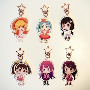 Könnte beinhalten: Sechs Schlüsselanhänger mit Anime-Charakteren. Jeder Schlüsselanhänger zeigt ein anderes Charakterdesign mit leuchtenden Farben und detaillierten Outfits. Die Schlüsselanhänger sind an einem silberfarbenen sternförmigen Verschluss befestigt.