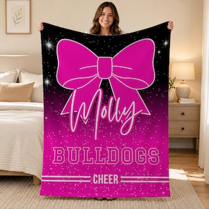 May include: A rectangular fleece blanket featuring a large hot pink bow graphic on a black and pink gradient background with white sparkles. The text Molly is written in a white script font, followed by the word BULLDOGS and the word CHEER.