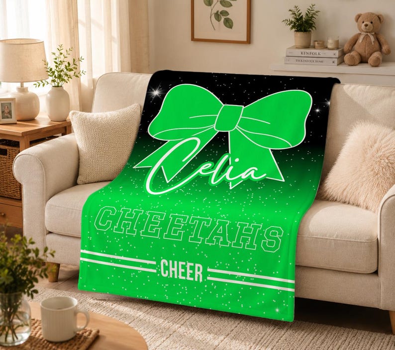 May include: A soft throw blanket featuring a large bright green bow graphic on a black and green gradient background with white glitter accents. The text Celia is written in script, followed by the block text CHEETAHS and the word CHEER.
