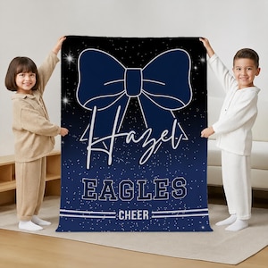 May include: A rectangular blanket featuring a dark blue background with a white starfield pattern. A large navy blue cheer bow graphic is centered at the top. The text "Hazel" is written in white script, followed by "EAGLES" and "CHEER" in white block letters.