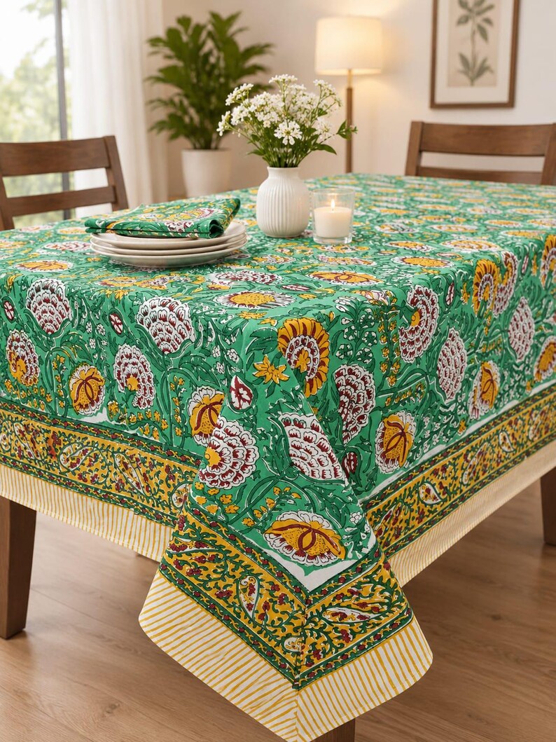 May include: A rectangular tablecloth featuring a vibrant green base with a repeating floral pattern in shades of yellow, white, and deep red. The border displays a yellow and green paisley design with a striped yellow and white edge finish.