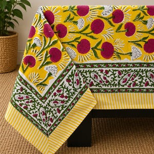 May include: A rectangular tablecloth featuring a bright yellow background with a repeating pattern of magenta flowers and white accents. The border displays a green vine motif with magenta floral details and a yellow and white striped edge.