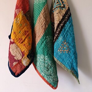 Peut inclure: Trois pièces de tissu rectangulaires présentant des coutures kantha complexes et des motifs en patchwork. La pièce de gauche affiche des motifs floraux jaunes, rouges et marron. La pièce centrale est verte avec des accents beige. La pièce de droite est bleue avec des formes géométriques.