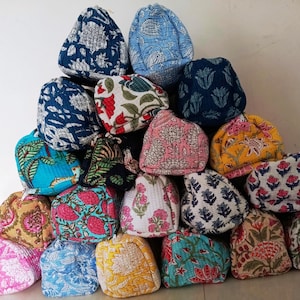 Könnte beinhalten: Eine Sammlung von Steppstoffhüten in verschiedenen Farben und floralen Mustern. Die Hüte sind pyramidenförmig gestapelt und zeigen eine Vielzahl von Designs, darunter Blau, Rosa, Gelb und Grün. Die Hüte scheinen handgefertigt zu sein.