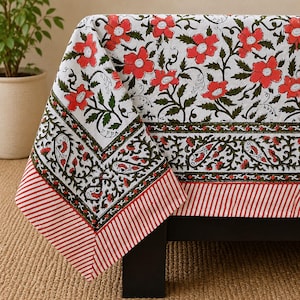 May include: A white tablecloth featuring a repeating pattern of red flowers and green vines. The border includes a decorative band of green paisley motifs and a final edge of red and white diagonal stripes, creating a structured visual design.