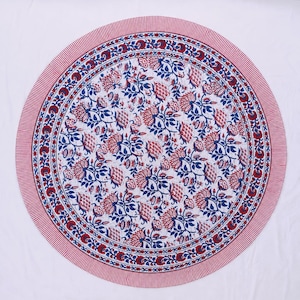May include: A round tablecloth featuring a white background with a repeating floral pattern in red and blue. The central design consists of intricate blossoms and leaves, surrounded by a circular border of smaller flowers and a thin red striped edge.