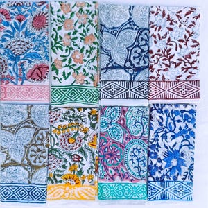 Könnte beinhalten: Eine Sammlung von zehn rechteckigen, gefalteten Textilien mit floralen Mustern. Die Textilien weisen eine Vielzahl von Farben auf, darunter Blau, Rosa, Orange, Gelb und Grün, mit weißen Hintergründen. Jedes Textil hat einen gemusterten Rand.