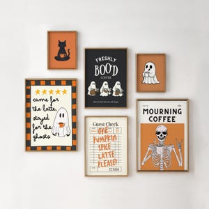 May include: A gallery wall set of six framed prints featuring Halloween-themed coffee illustrations. Designs include a black cat, ghosts with the text FRESHLY BOO'D COFFEE, a ghost with text came for the latte, stayed for the ghosts, a guest check with text ONE PUMPKIN SPICE LATTE PLEASE, and a skeleton with MOURNING COFFEE text.