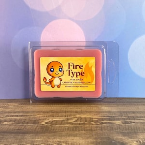May include: A rectangular wax melt in a clear plastic container. The wax is a light red color. A yellow label features a cartoon character, the words "Fire Type", and "Campfire + Marshmallow". The Etsy shop name is also included.