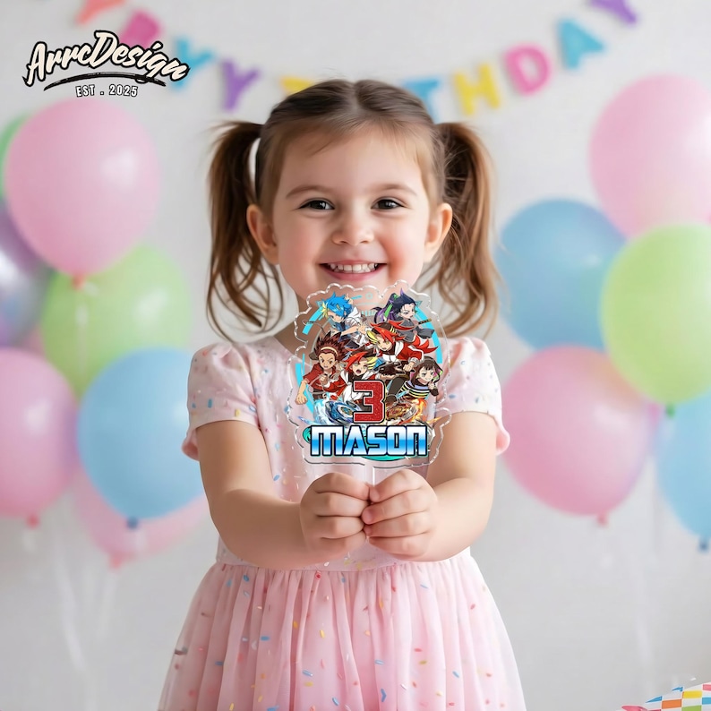 K&ouml;nnte beinhalten: Ein klarer Acryl-Kuchenaufsatz mit einem bunten Cartoon-Design, der Zahl "3" und dem Namen "MASON". Ein junges M&auml;dchen in einem rosa Kleid h&auml;lt den Aufsatz, mit Luftballons im Hintergrund. Das ArreDesign-Logo befindet sich oben links.