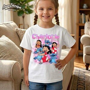 May include: A white short-sleeved t-shirt featuring a colourful graphic print of Lilo and Stitch characters with the name Charlotte in pink lettering above the design. The shirt has a crew neckline and a standard fit, showcasing a vibrant cartoon scene.